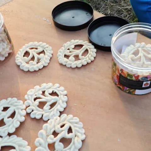 Round, lace-like Gohona Bori set out on a board to dry, beside jars of finished bori