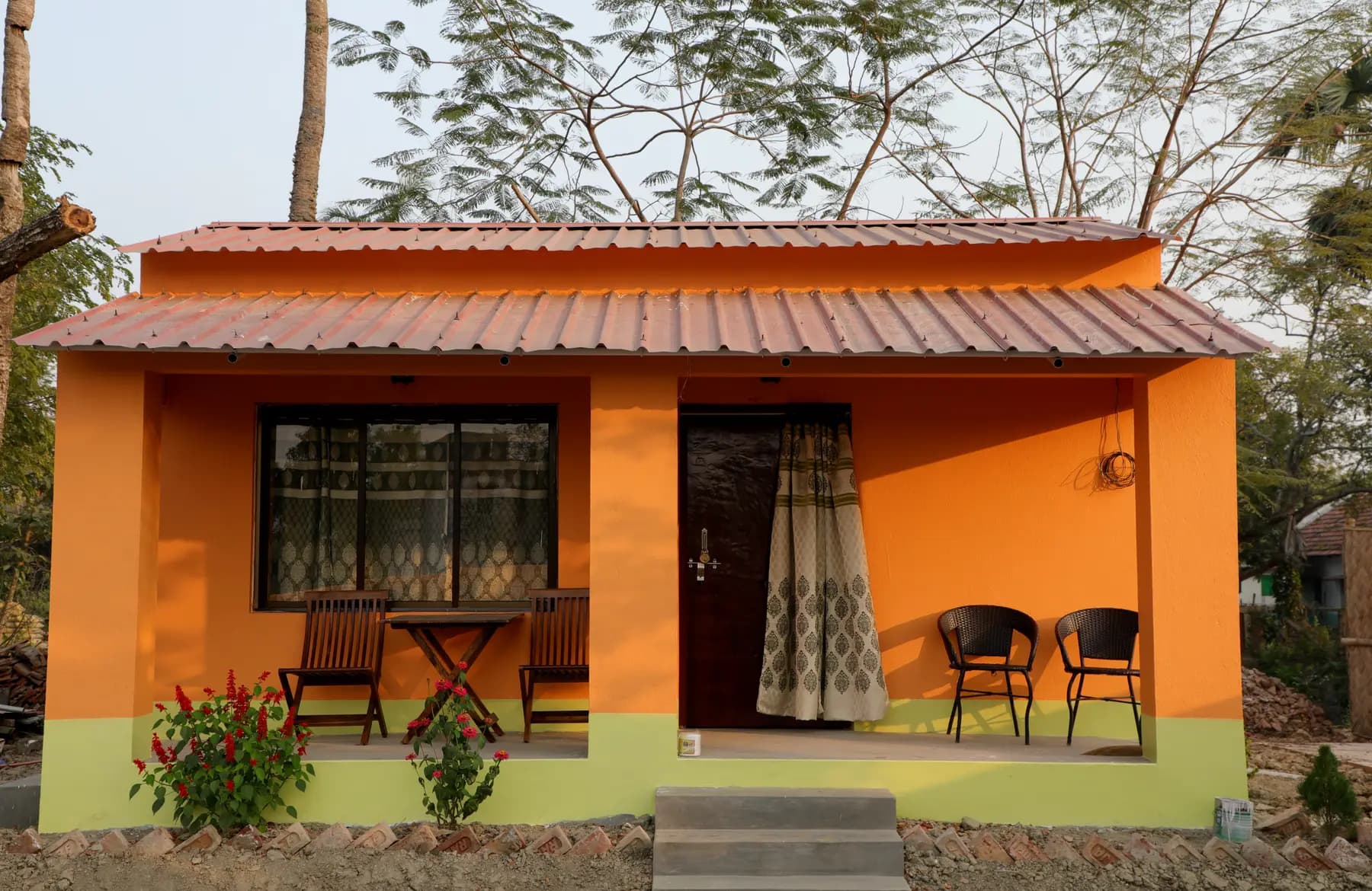 The Garden House: an orange guest cottage with tin roof and veranda chairs