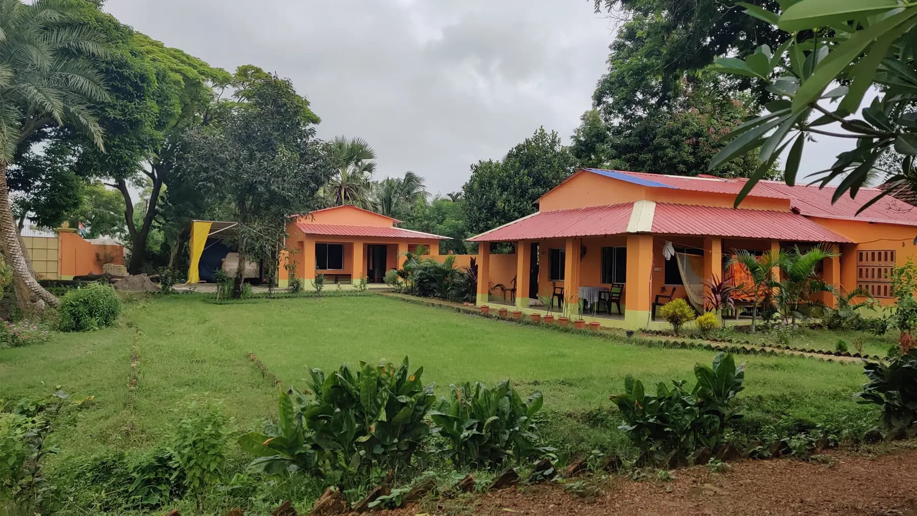 Two orange houses with red tin roofs around a green lawn at Turiyo