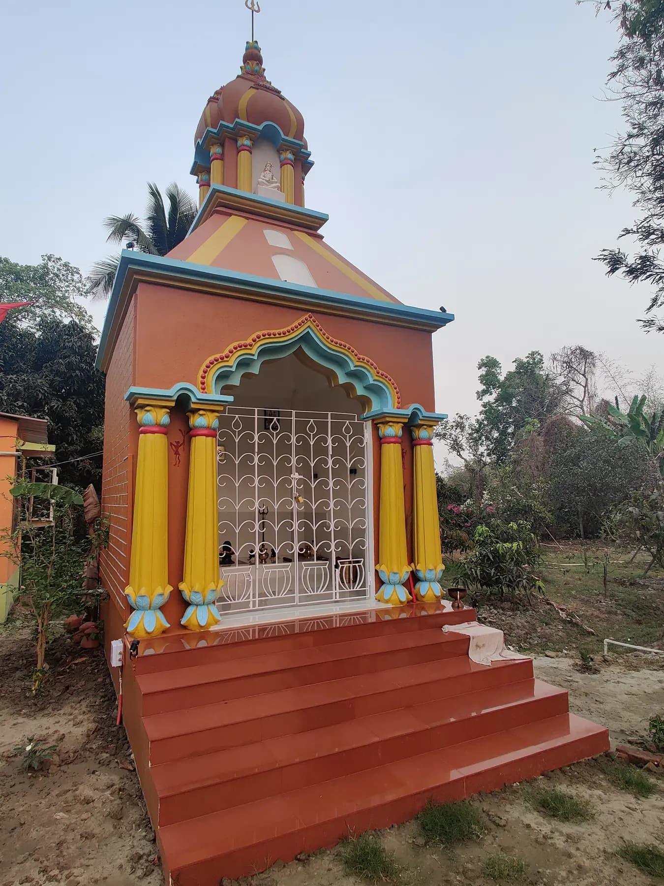 The Siva Mandir at Turiyo, a small painted temple with yellow pillars and red steps