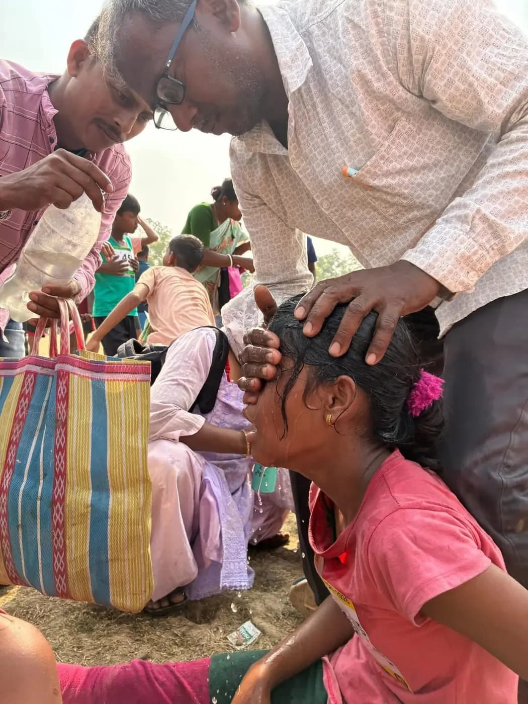 A volunteer pours water over a girl runner’s head to cool her down after she finishes