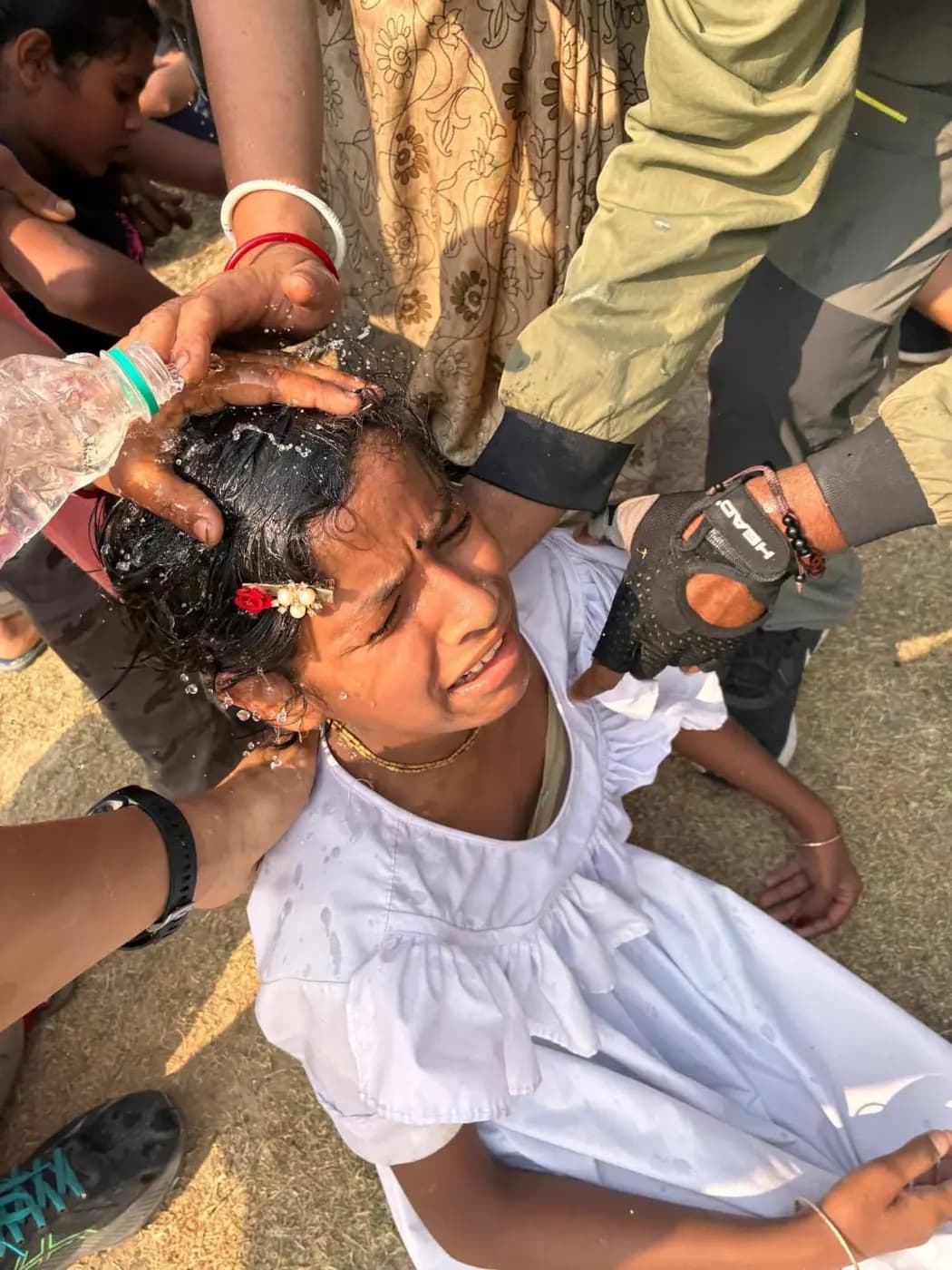 Helpers pour water over a girl in a white dress who has just finished the race