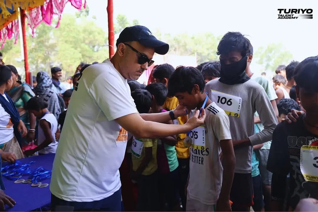 A volunteer in a cap puts finisher medals round the necks of young runners