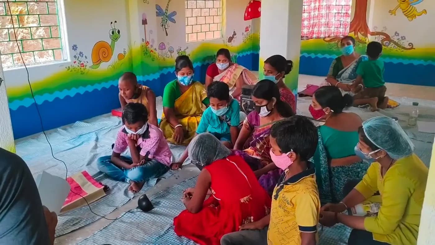 Women and children in a painted classroom around a smart speaker