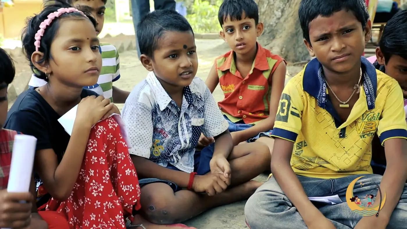 Children sitting together listening in an outdoor class