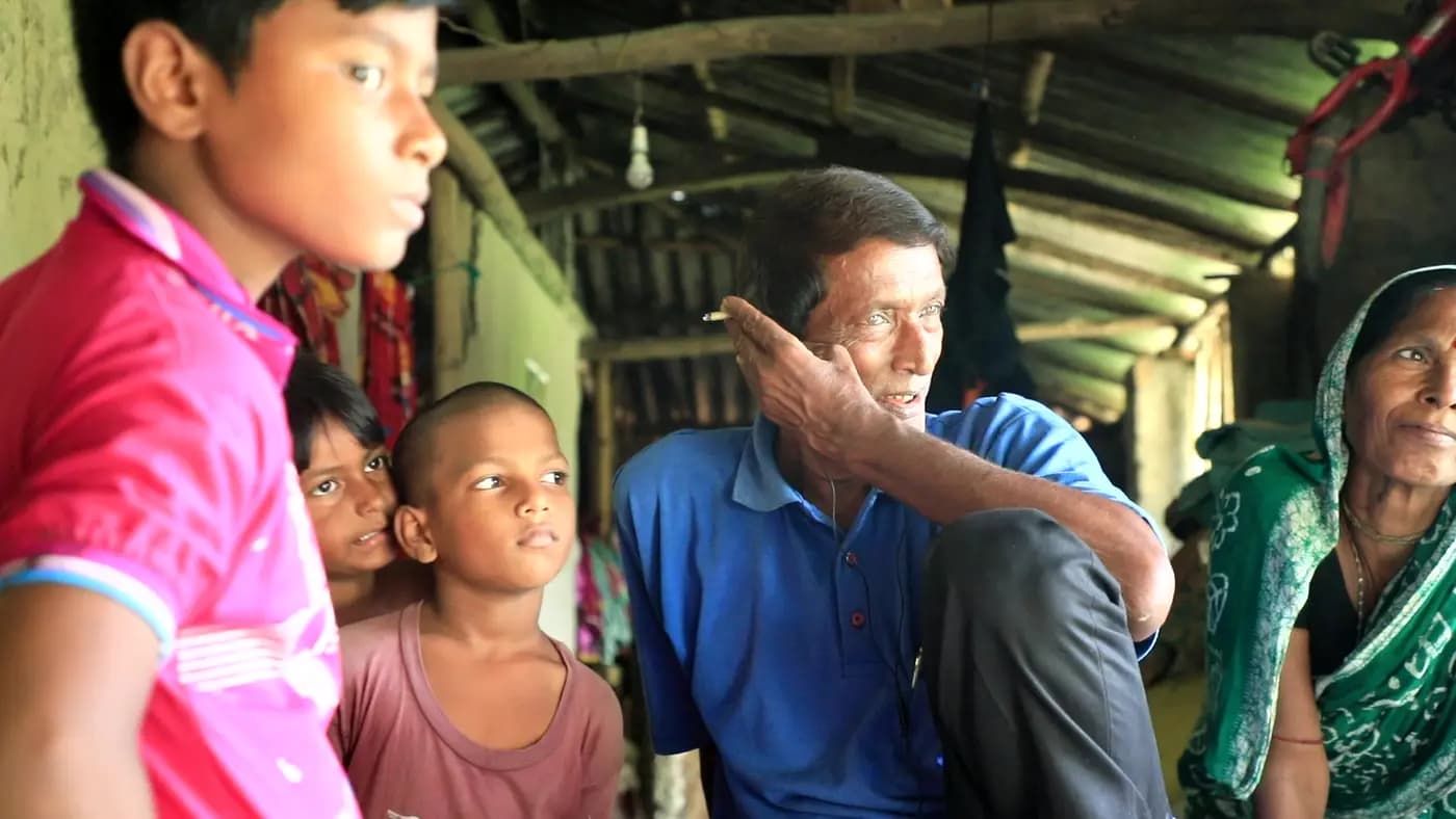 Benu Kishore Nayek talking with children and a woman at his home