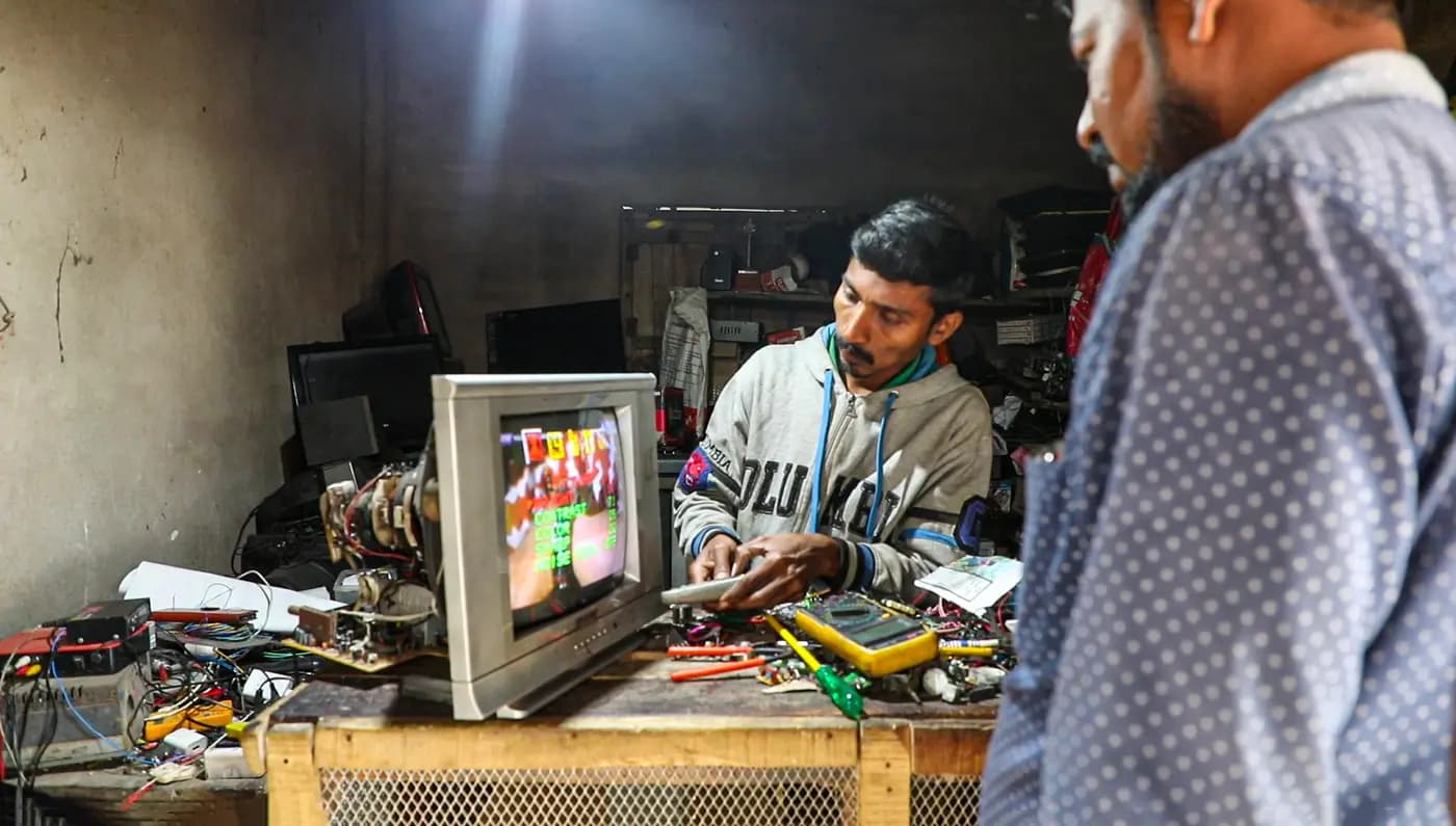 Technician repairing a television in a village electronics shop