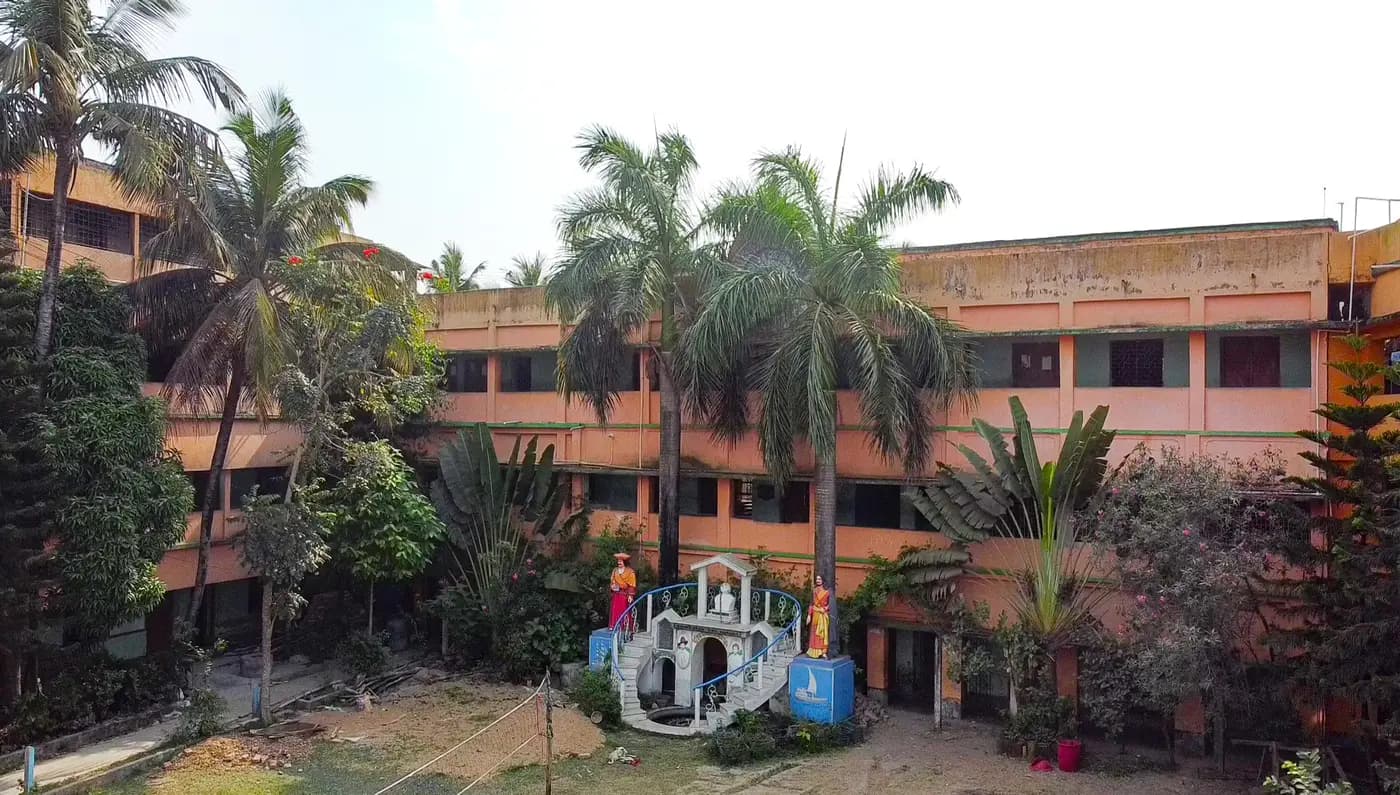 Holudbari High School building with palm trees and garden shrine