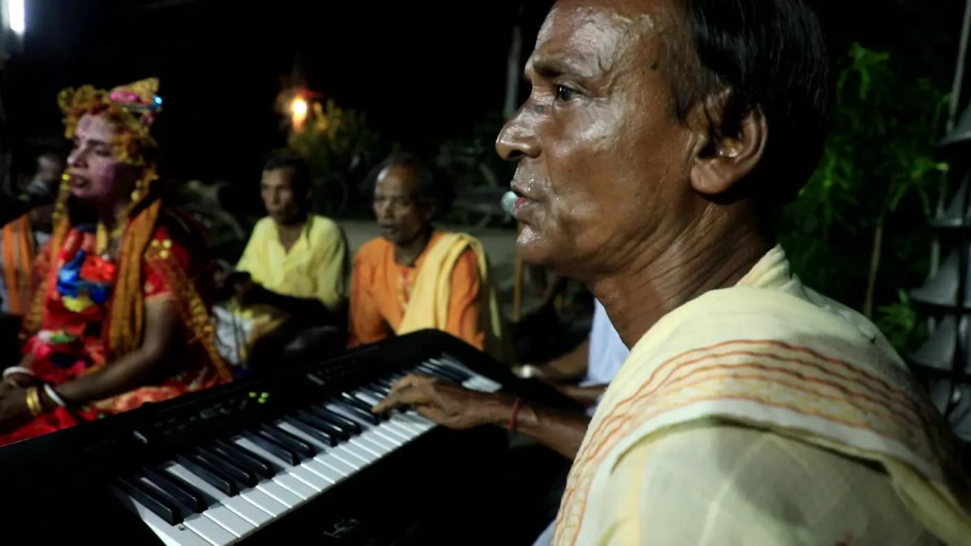 Keyboard player and costumed singer at a night kirtan