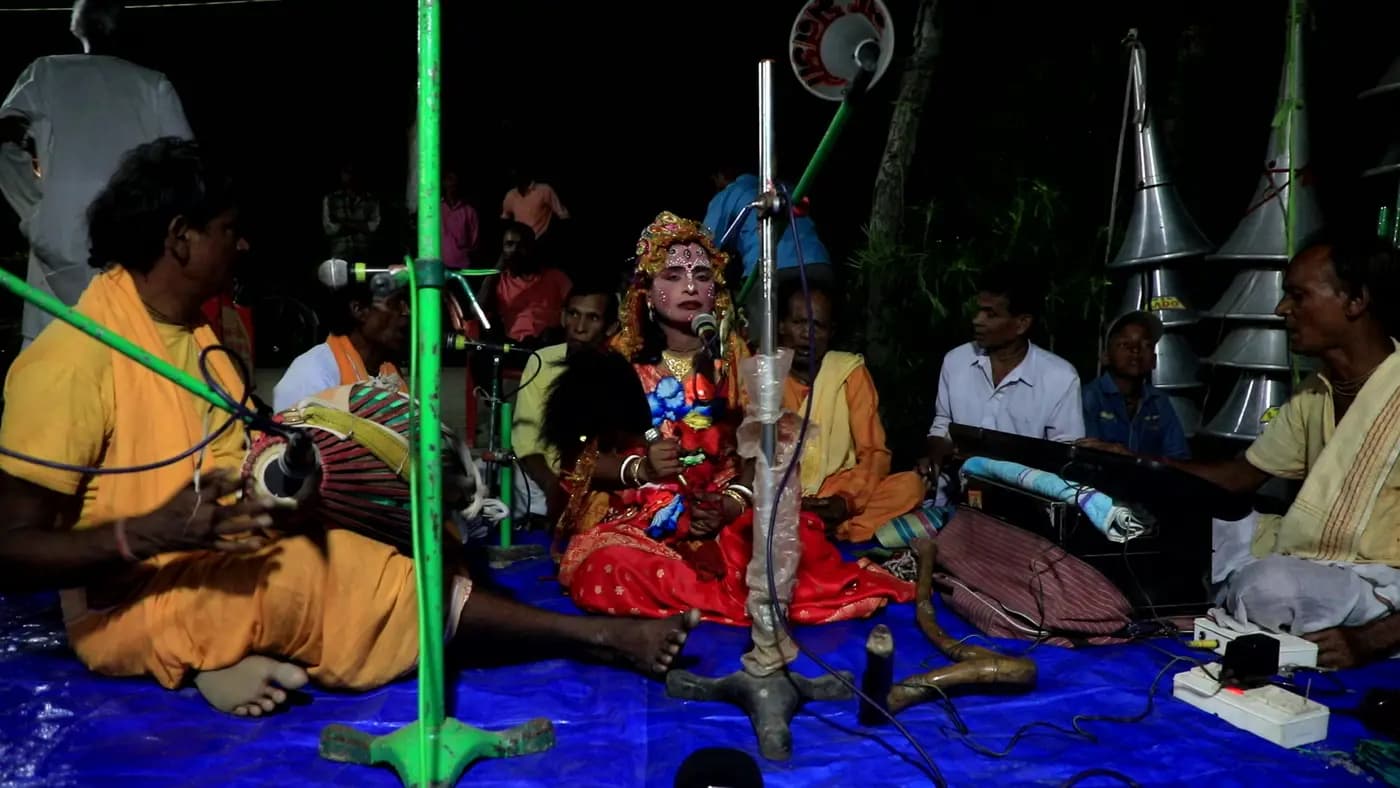 Musicians and costumed singer performing at a night puja