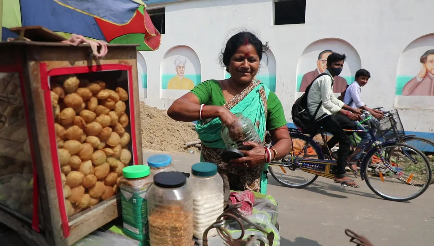 Panipuri seller at her cart as schoolboys cycle past