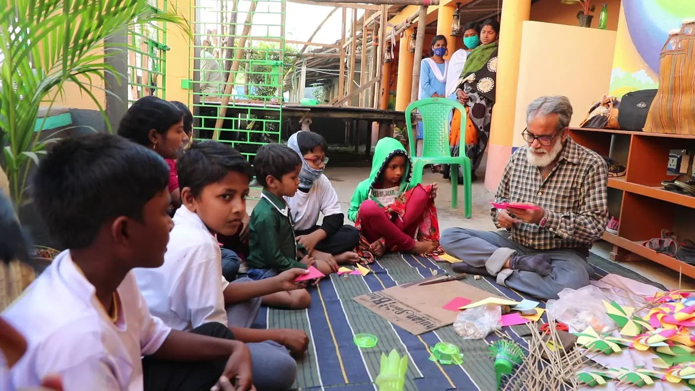 Children watching Sudip Maiti make paper crafts