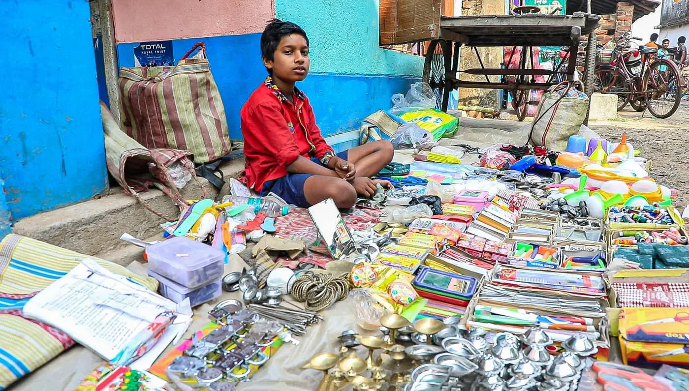 Boy at a haat stall of stationery and household goods