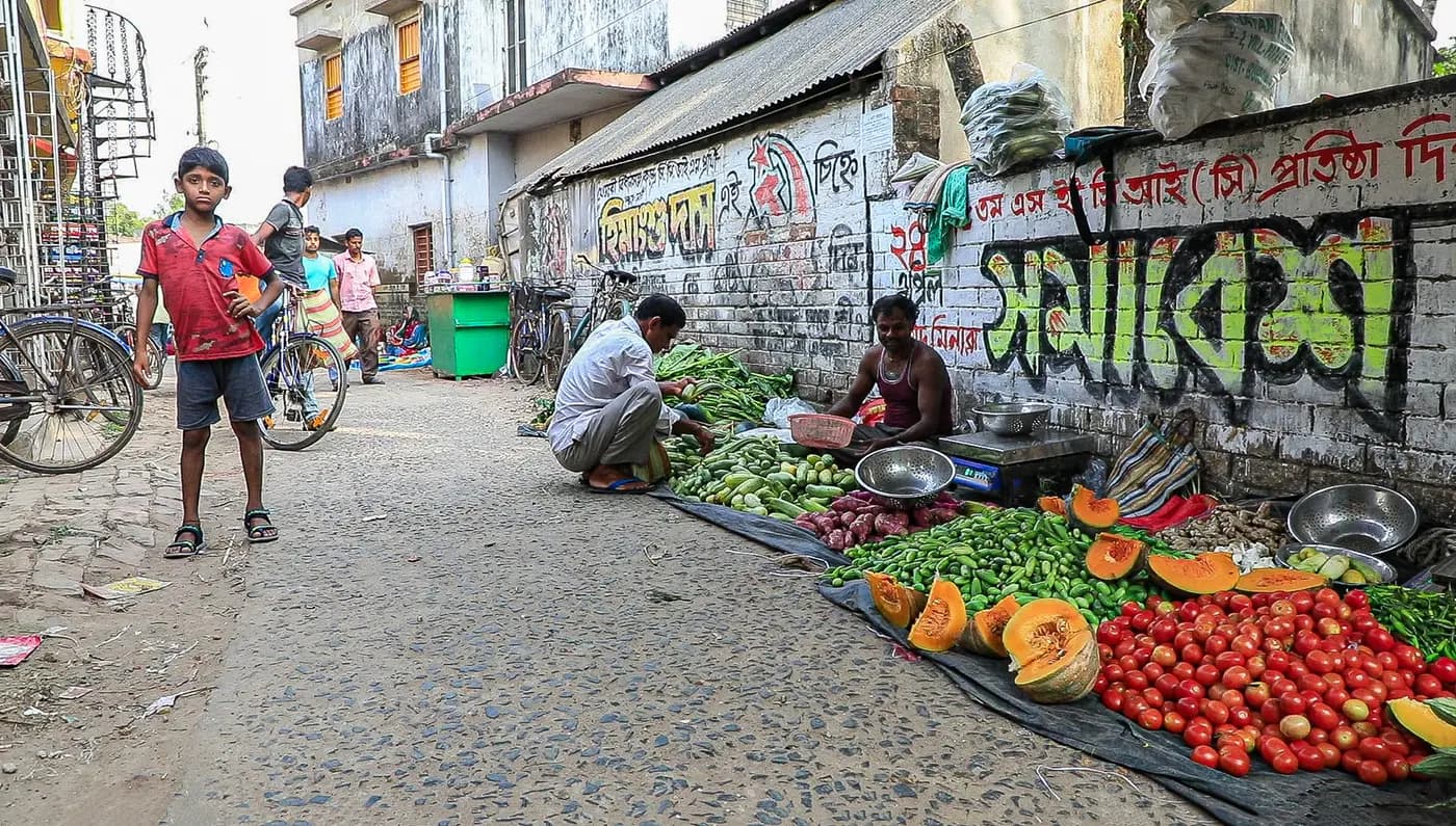 Vegetable sellers along a painted wall at the haat