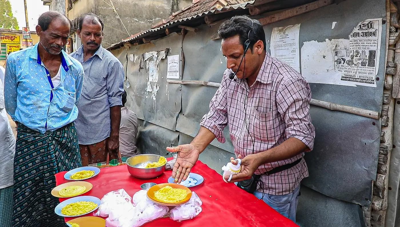 Vendor with headset demonstrating his goods at the haat