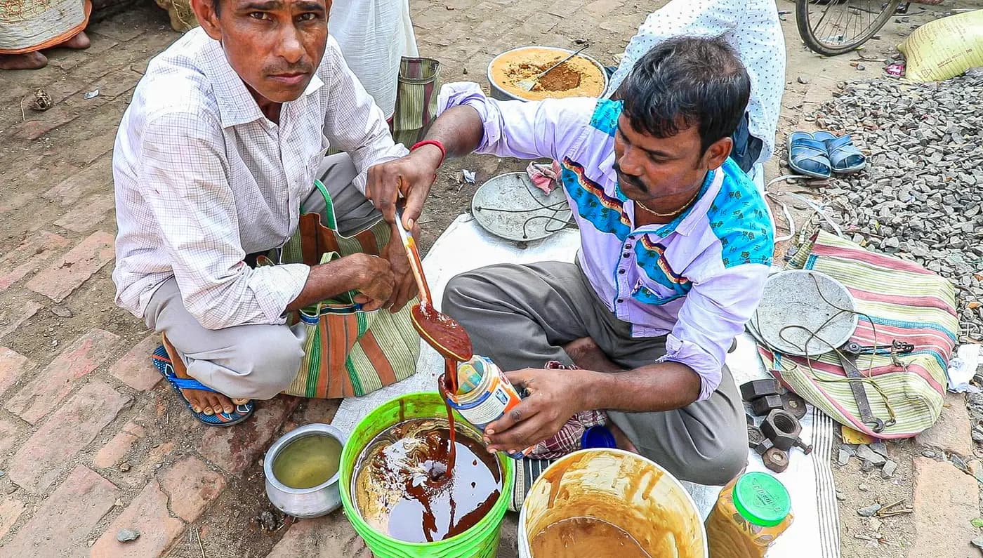 Seller pouring jaggery syrup into a jar at the haat