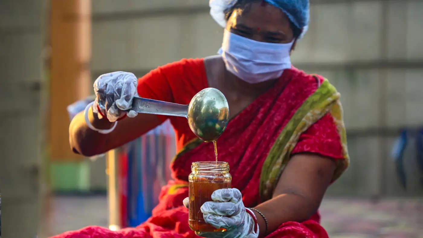 Woman in gloves ladling pickle into a jar