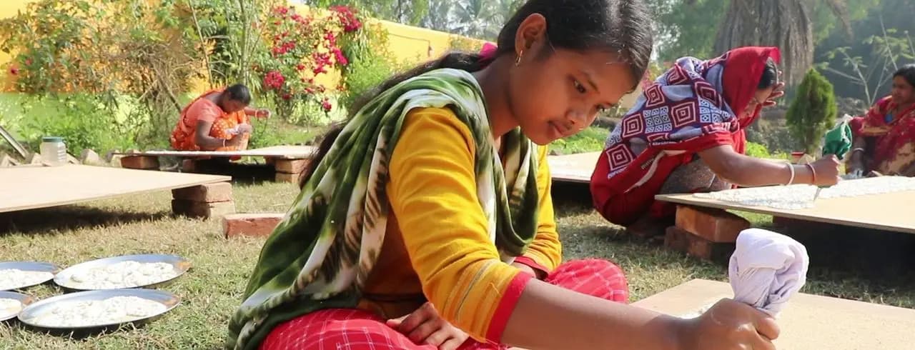 Young woman piping Gohona Bori onto drying boards