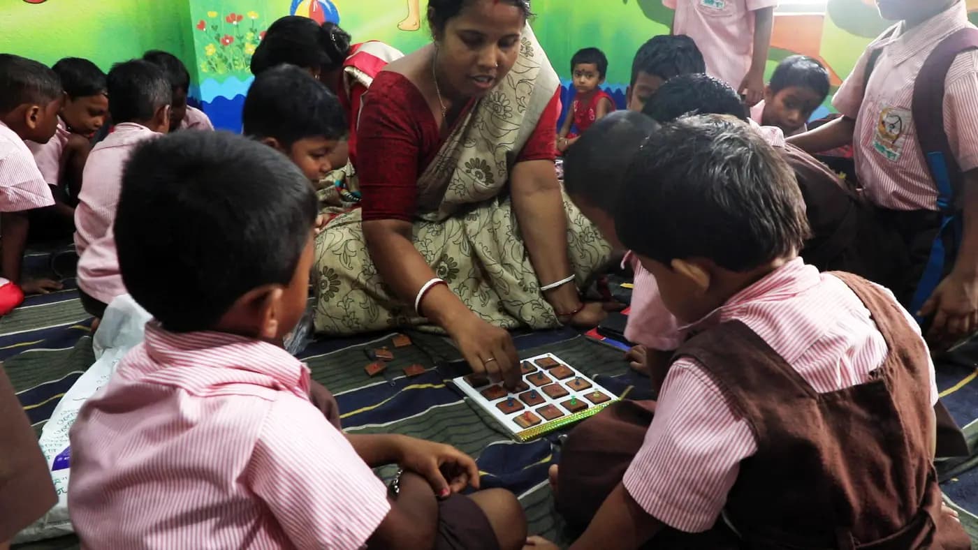 Teacher and children with a learning kit in a classroom