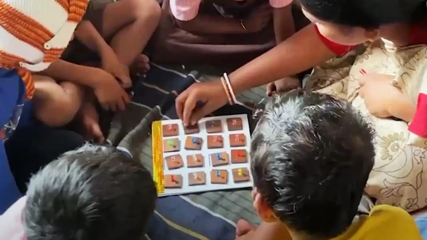 Children using a board learning kit with a teacher