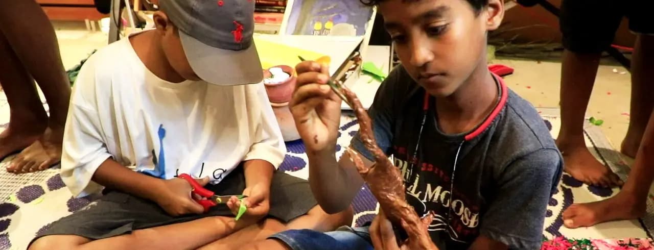 Boys making a craft model with scissors and a glue gun