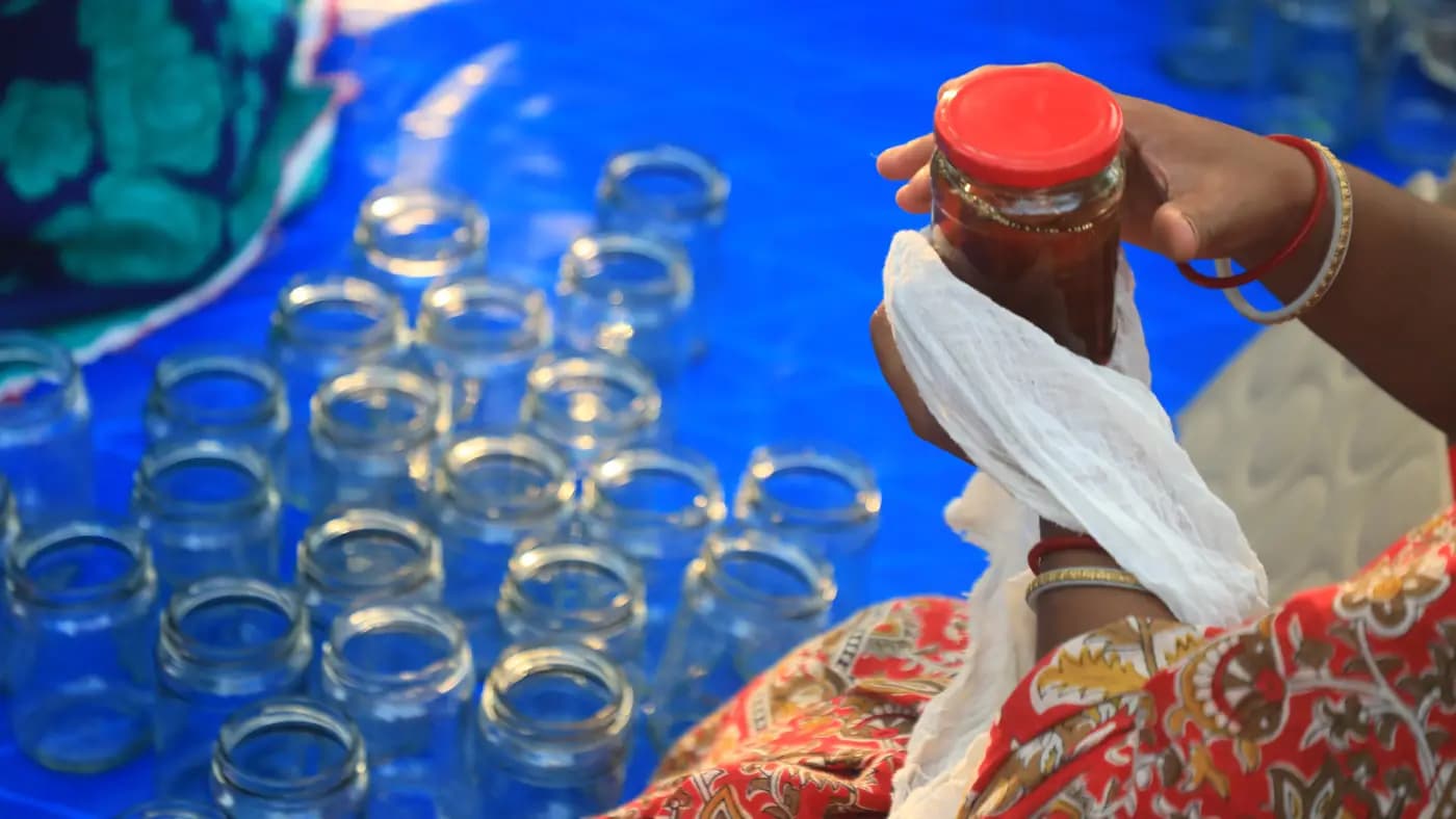 Jar of Turiyo Foods preserve held above empty jars