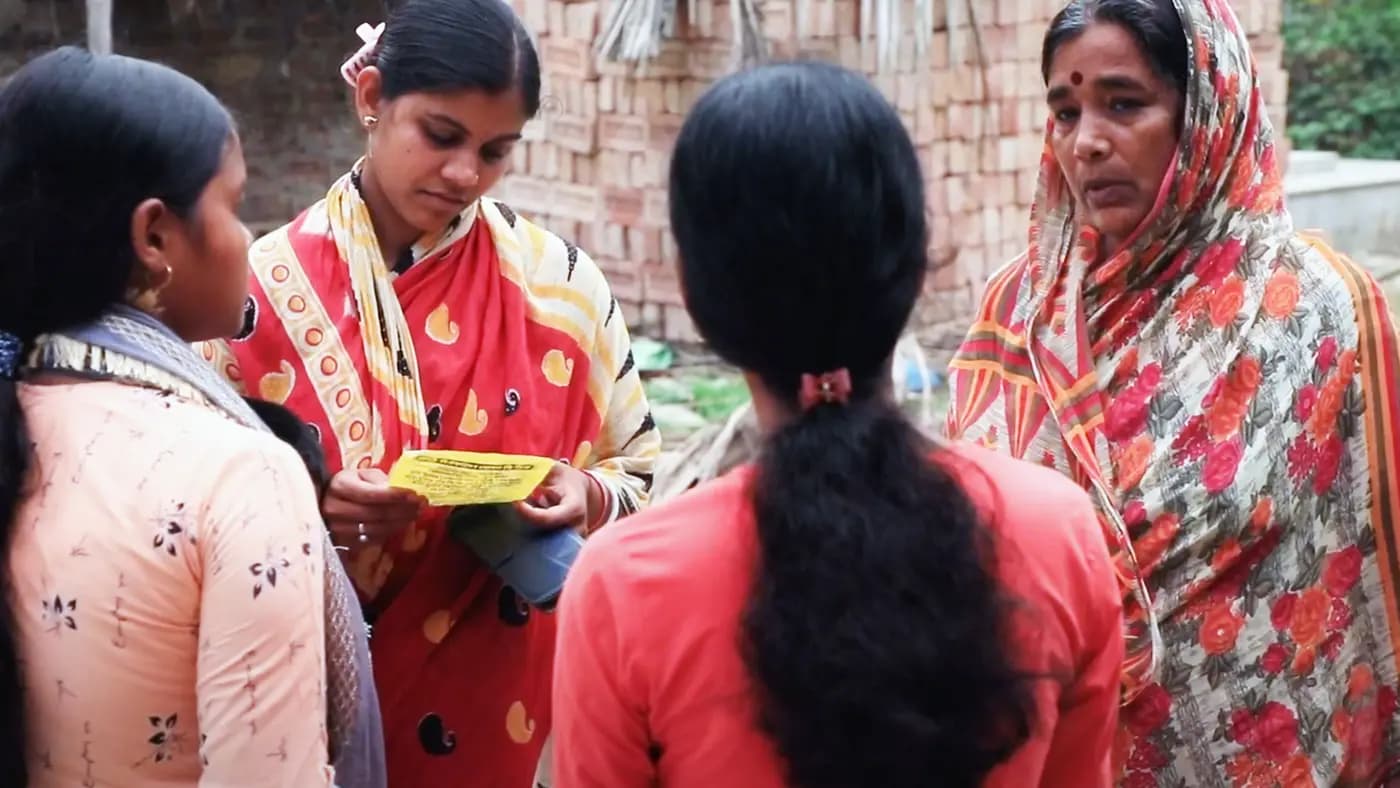 Health worker explaining a clinic leaflet to village women