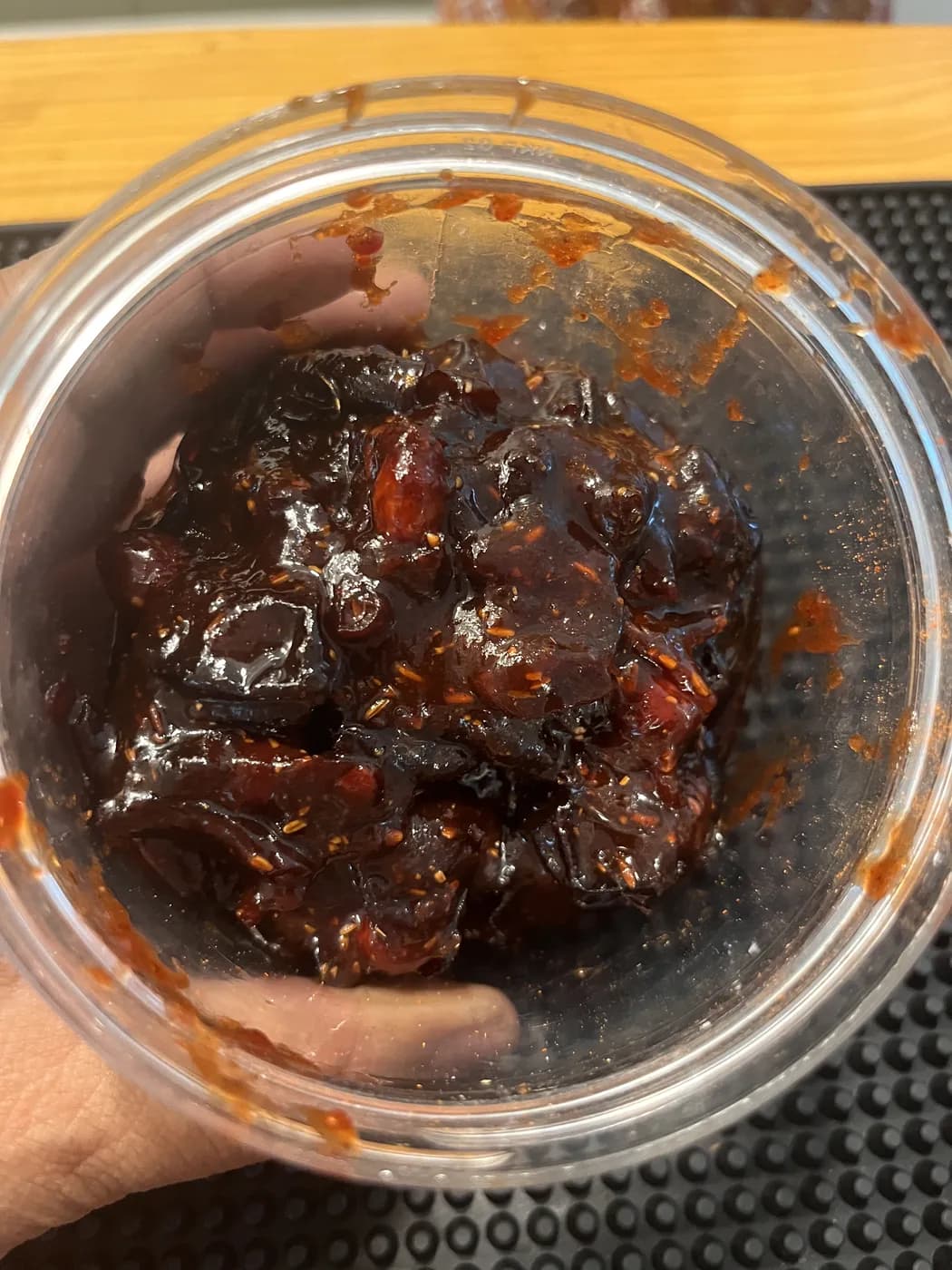 A tub of Kuler Achar: whole jujubes glossy in a dark, spiced syrup