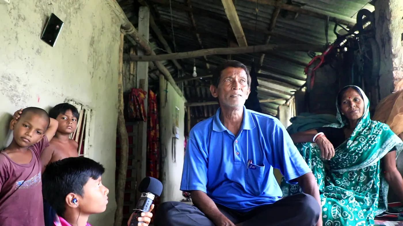 Benu Kishore Nayek being interviewed at home by a boy with a microphone
