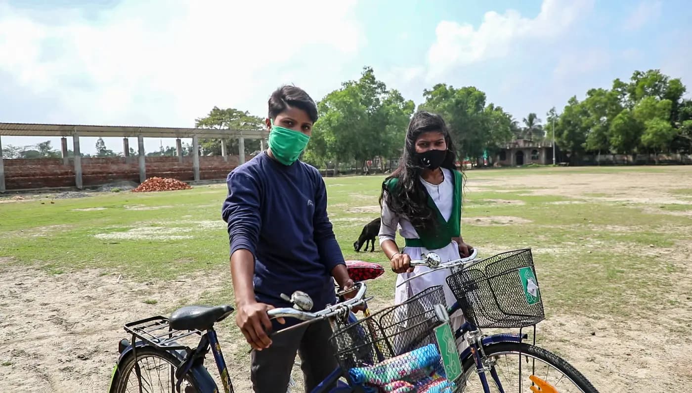 Two girl football champions with bicycles on the school field
