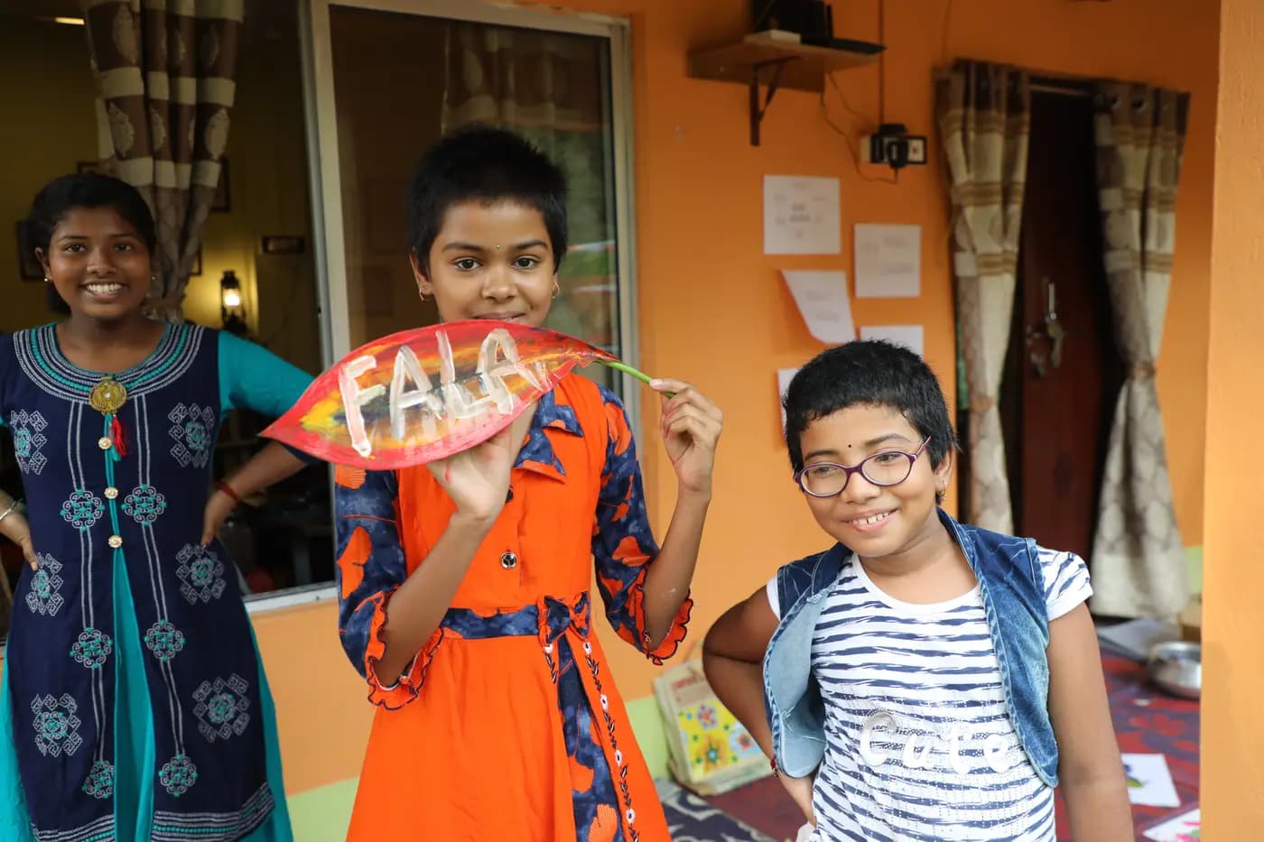 Girls holding a painted leaf reading FALA